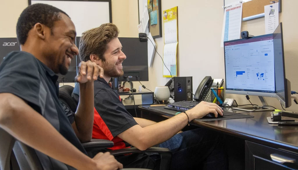 SEO Technicians smiling at a computer screen