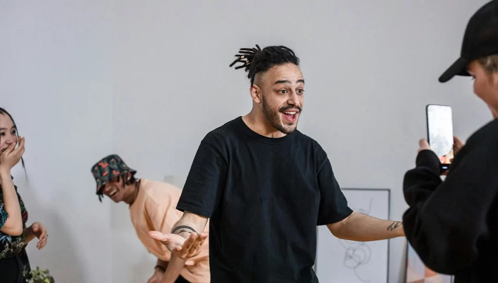 A man performing infront of a cellphone with people behind him