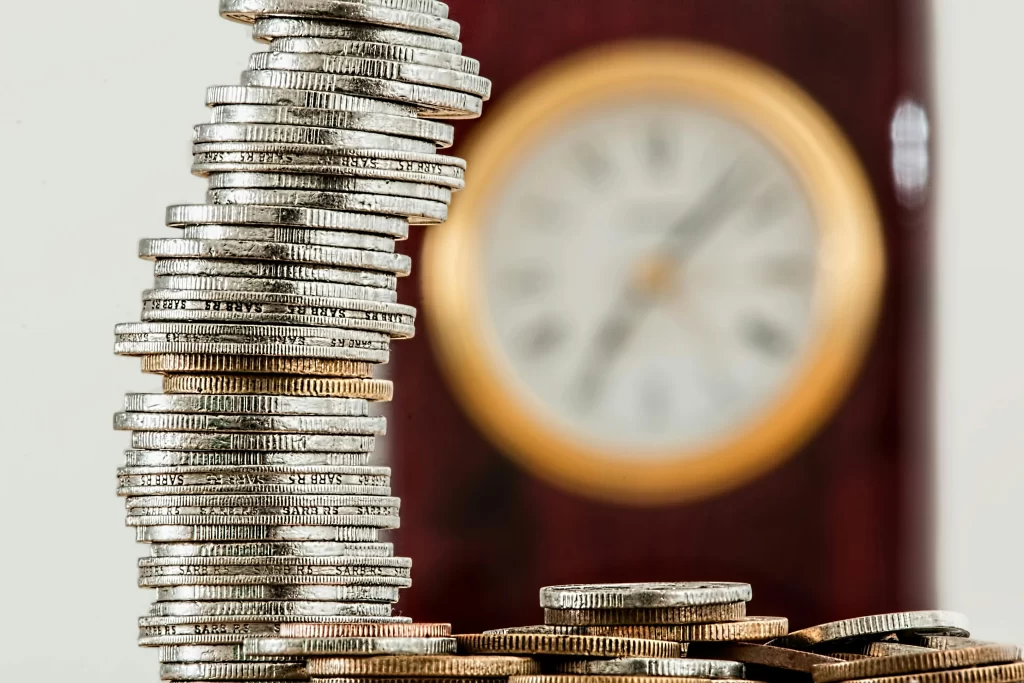 a stack of coins infront of a blurry clock in the background