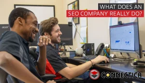 Two men smiling while looking at a computer screen