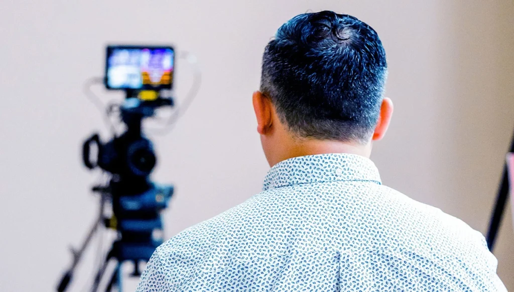 A man in a studio setting preparing to operate a camera on a tripod
